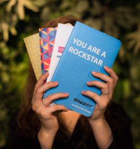 multiple notebooks being held in front of leaves. Meerder notitieboeken die worden vastgehouden voor bladeren. tree-free notebooks, dopper, EU, Red bull, paper alternative, notebook A5, stone paper notebooks, steenpapieren notitieboeken, sustainable gift, duurzaam cadeau, duurzaam relatiegeschenk, sustainable corporate gif, promotional giftt